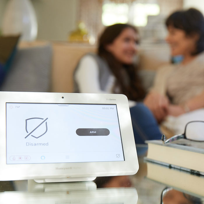 tablet with home security app on table with couple on couch in background
